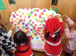 子どもたちがケーキに果物を貼るようす